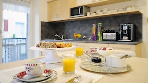 Een ontbijt met gebak, sinaasappelsap en een koffiezetapparaat in een moderne keuken.