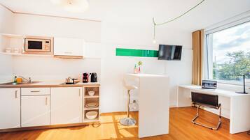 A modern kitchen with a microwave, coffee maker, and a small dining area with a bar stool.