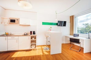 A modern kitchen with a microwave, coffee maker, and a small dining area with a bar stool. - Brera Serviced Apartments Nürnberg (Nuremberg)