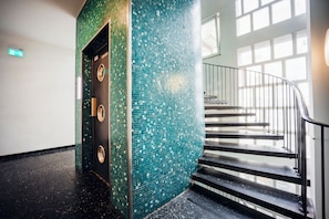A staircase with a glass railing and a wall with mosaic tiles. - Brera Serviced Apartments Nürnberg (Nuremberg)