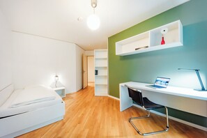 A modern bedroom with a bed, a desk with a laptop, and a chair. - Brera Serviced Apartments Nürnberg (Nuremberg)