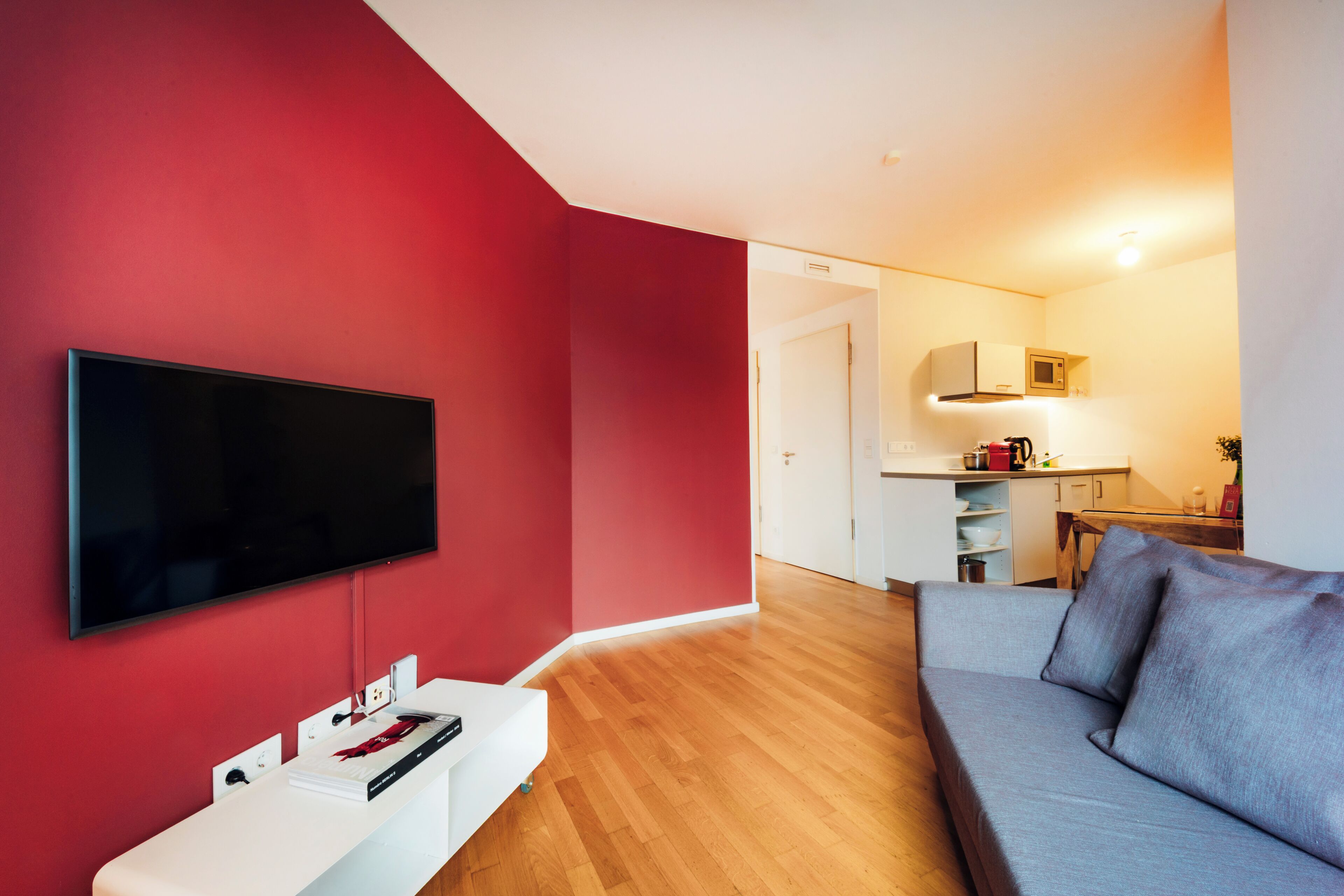 Una sala de estar moderna con un televisor de pantalla plana, una mesa de centro blanca y un sofá gris.