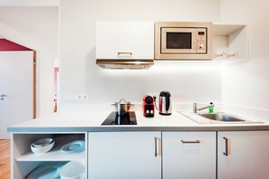 A modern kitchen with a microwave, kettle, and coffee machine on the countertop. - Brera Serviced Apartments Nürnberg (Nuremberg)