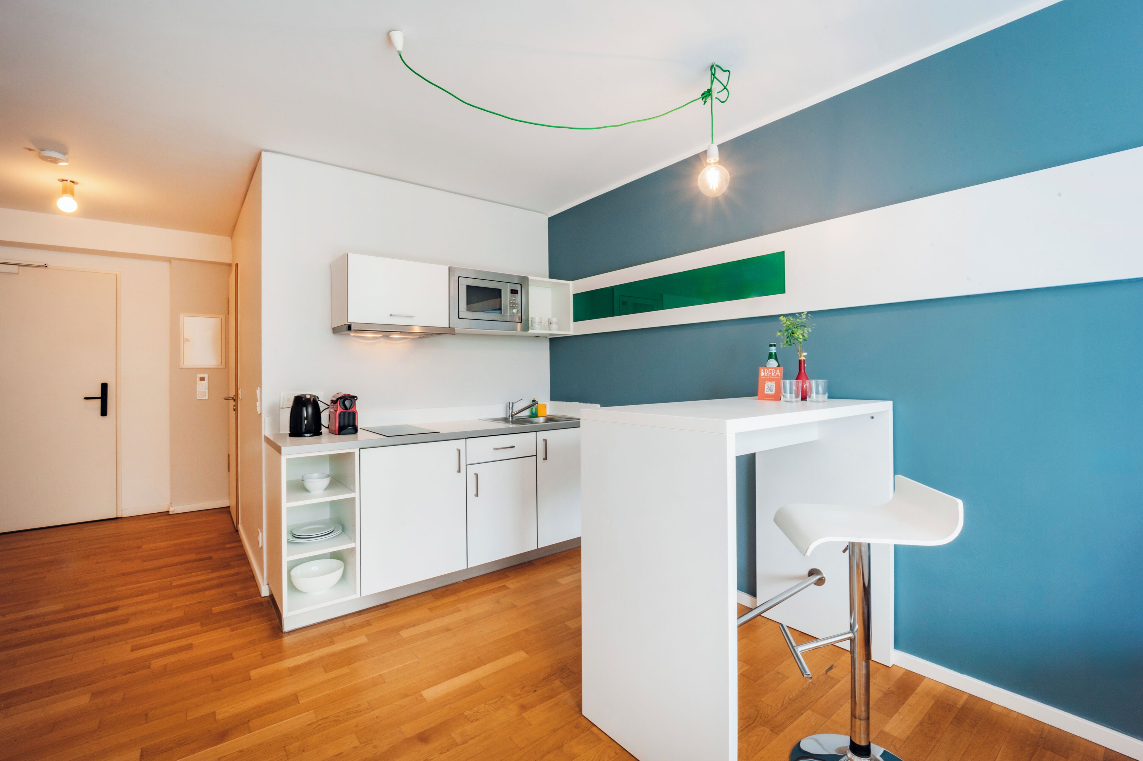 Eine moderne Küche mit weißen Schränken, einer Mikrowelle und einer Bar mit einem Hocker.
