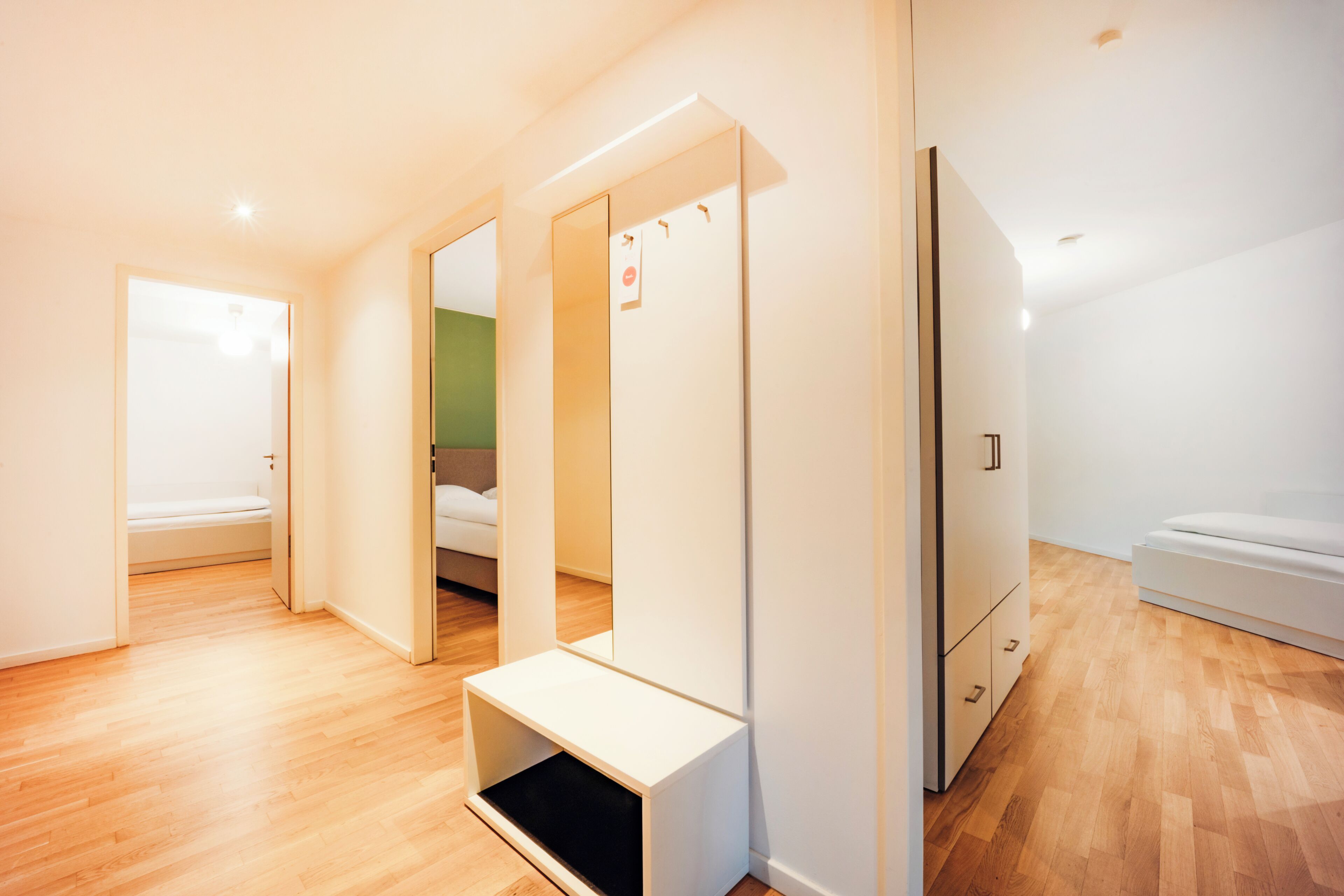 A modern, well-lit room with a bed, a wardrobe, and a bench.