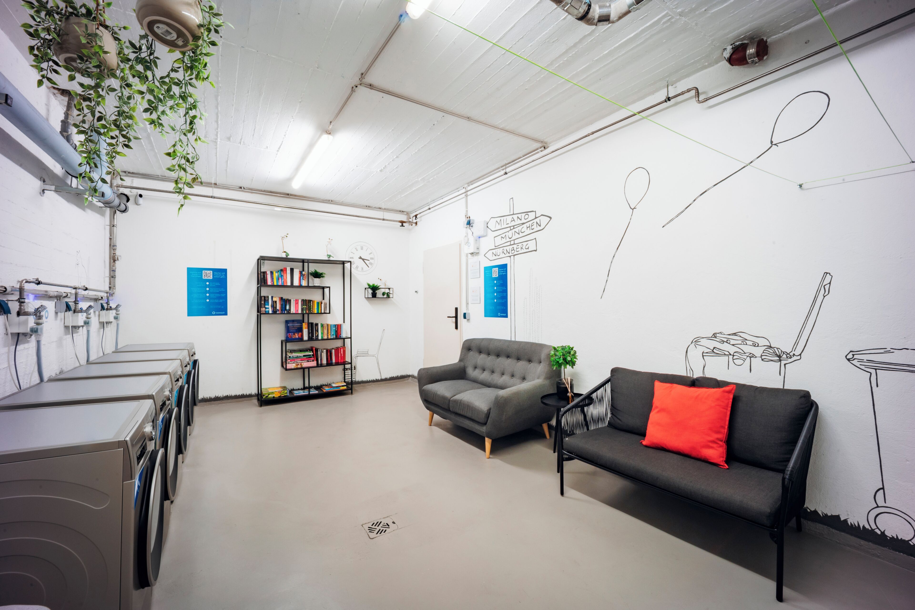 A modern, well-lit room with a sofa, a bookshelf, and a wall with directional signs.