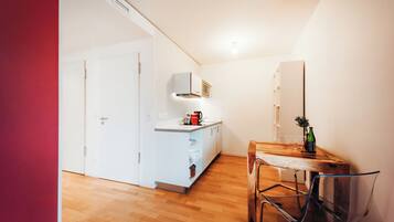 Una cocina compacta con una mesa de comedor de madera, una silla y un mueble pequeño.