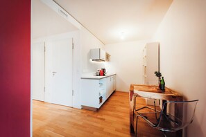 A compact kitchen with a wooden dining table, a chair, and a small cabinet.