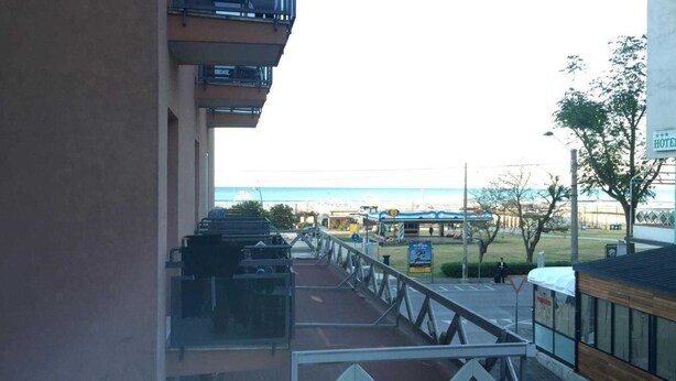 A hotel balcony with a view of the beach and a parking area. - Hostel Bella Rimini (Rimini)