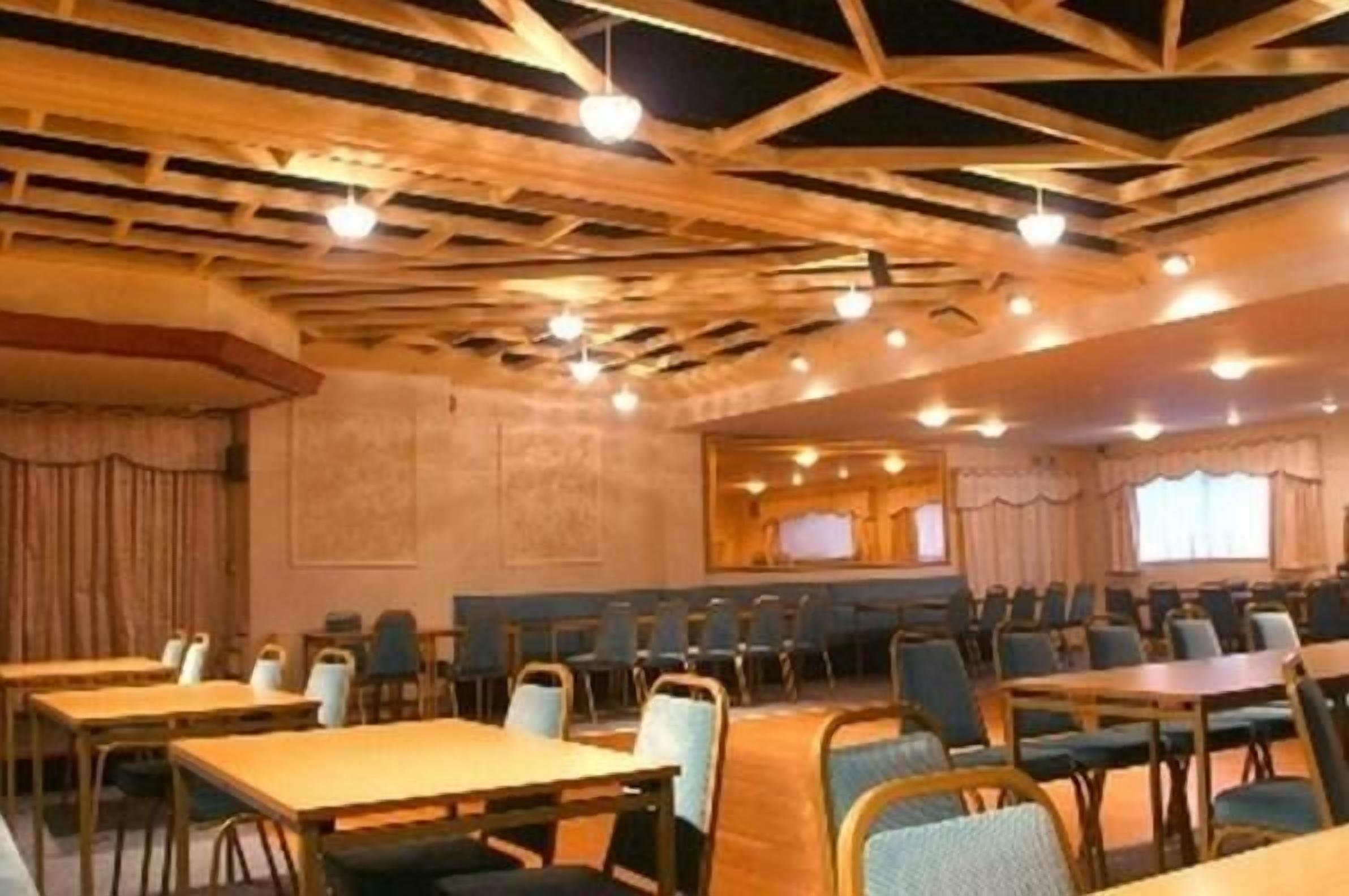 Una sala conferenze con travi in legno, tavoli e sedie disposte per riunioni.