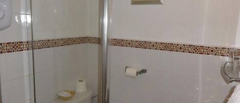 A bathroom with a toilet, a shower, and a sink.