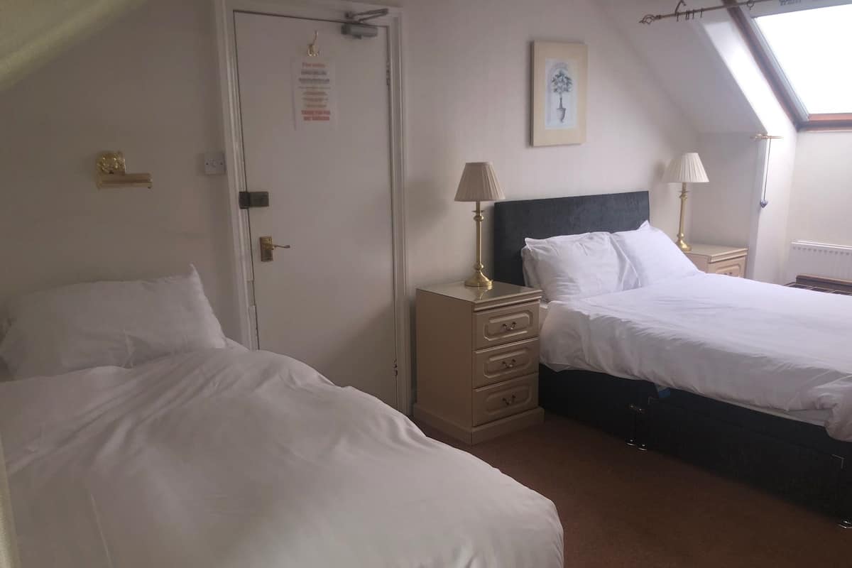 A bedroom with two beds, a dresser, and a door with a notice.