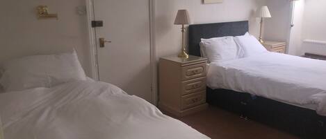 A bedroom with two beds, a dresser, and a door with a notice.