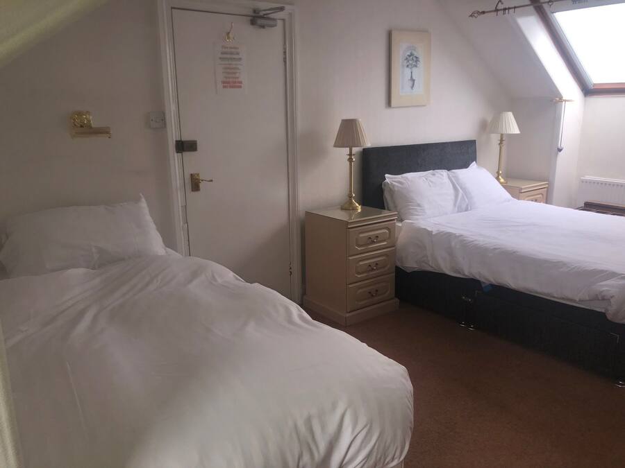 A bedroom with two beds, a dresser, and a door with a notice.