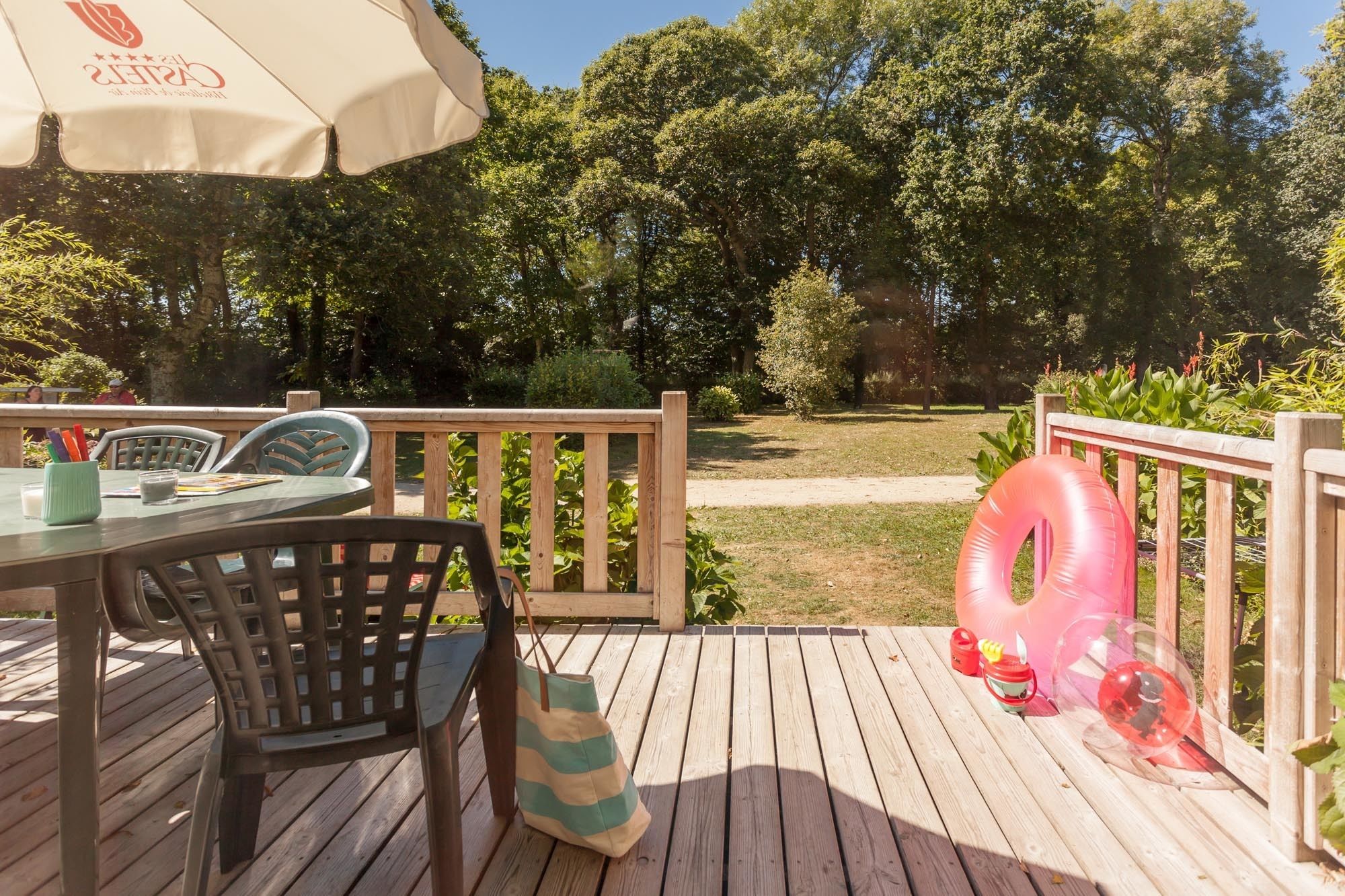 A wooden deck with outdoor furniture, including a table and chairs, and a large inflatable pool float.