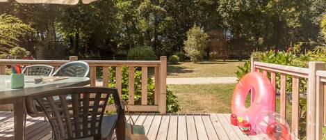 A wooden deck with outdoor furniture, including a table and chairs, and a large inflatable pool float.