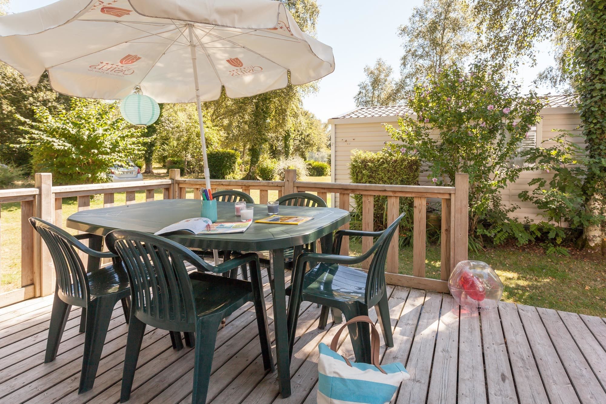 A round table with chairs, an umbrella, and a small table with a glass and a book.