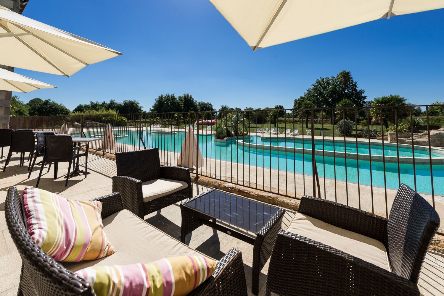 An outdoor patio with wicker furniture and a view of a swimming pool.