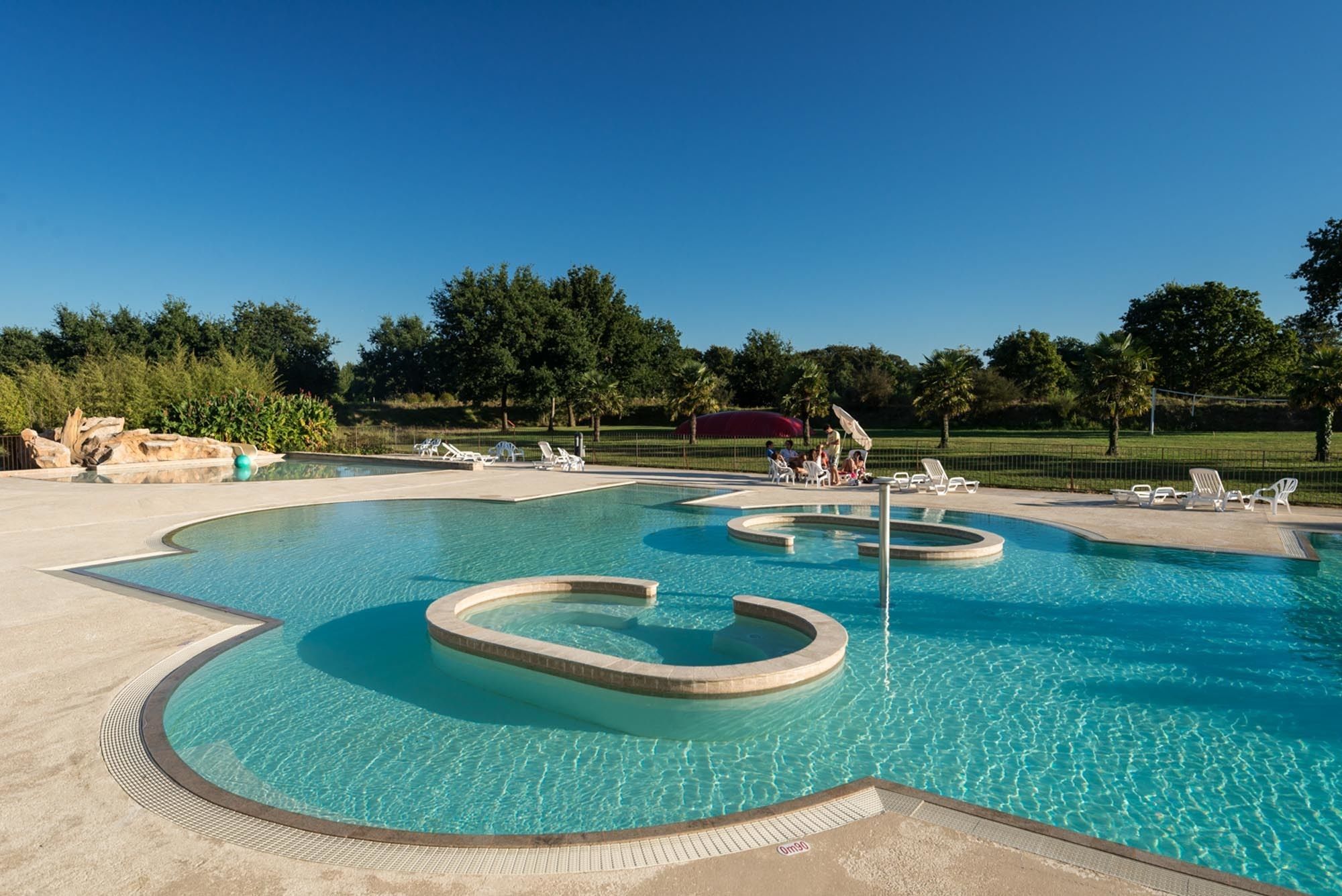 A swimming pool with multiple lanes and a surrounding deck area with lounge chairs.