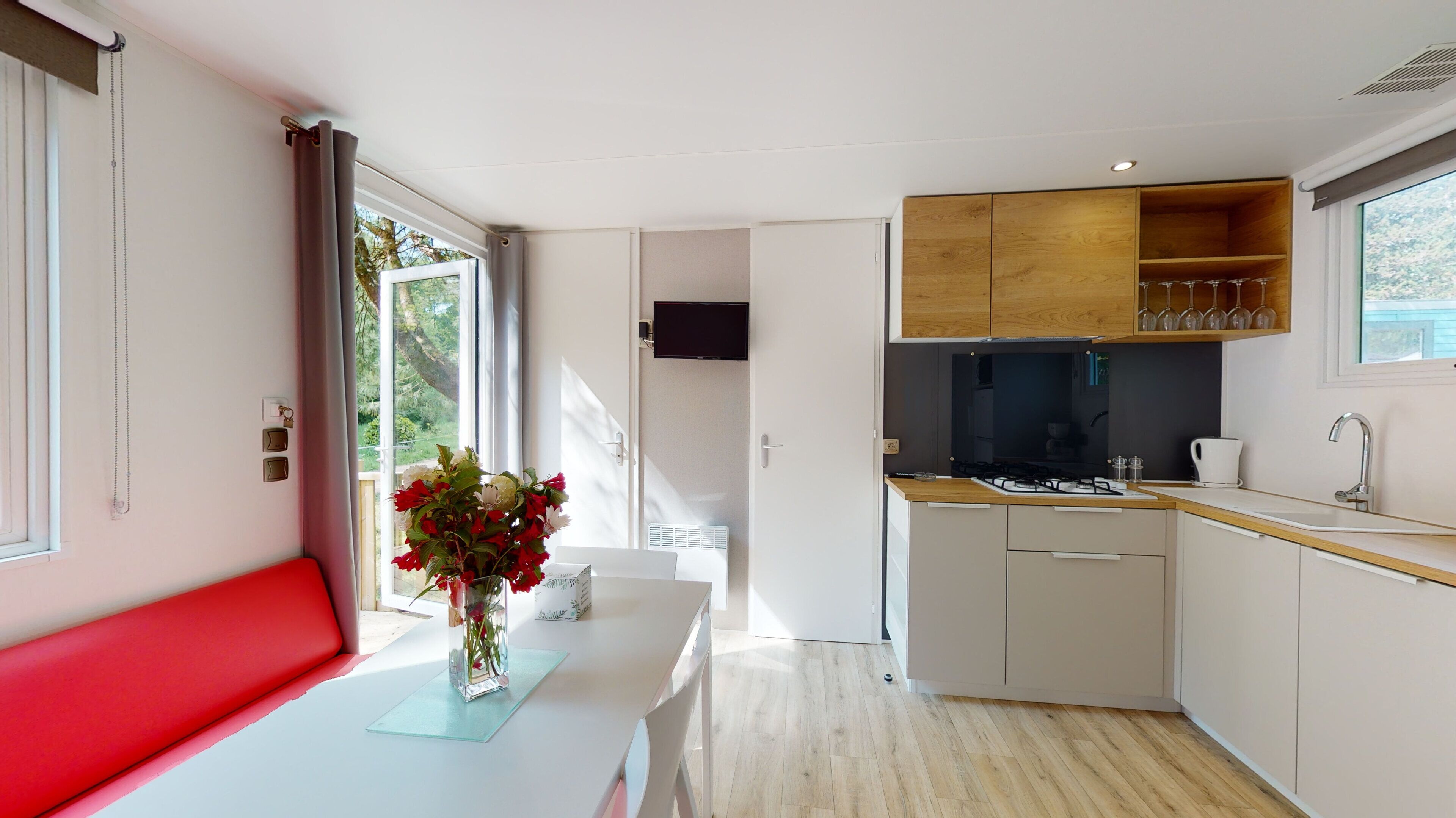 Une cuisine moderne avec des meubles en bois, une cuisinière encastrée et une fenêtre donnant sur un espace verdoyant.