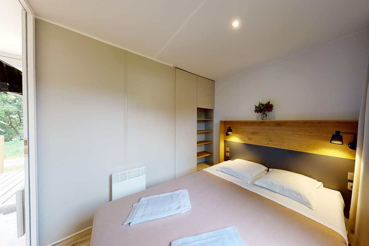 Un dormitorio moderno con una cama grande, estanterías empotradas, cabecera de madera y mesita de noche con lámpara.