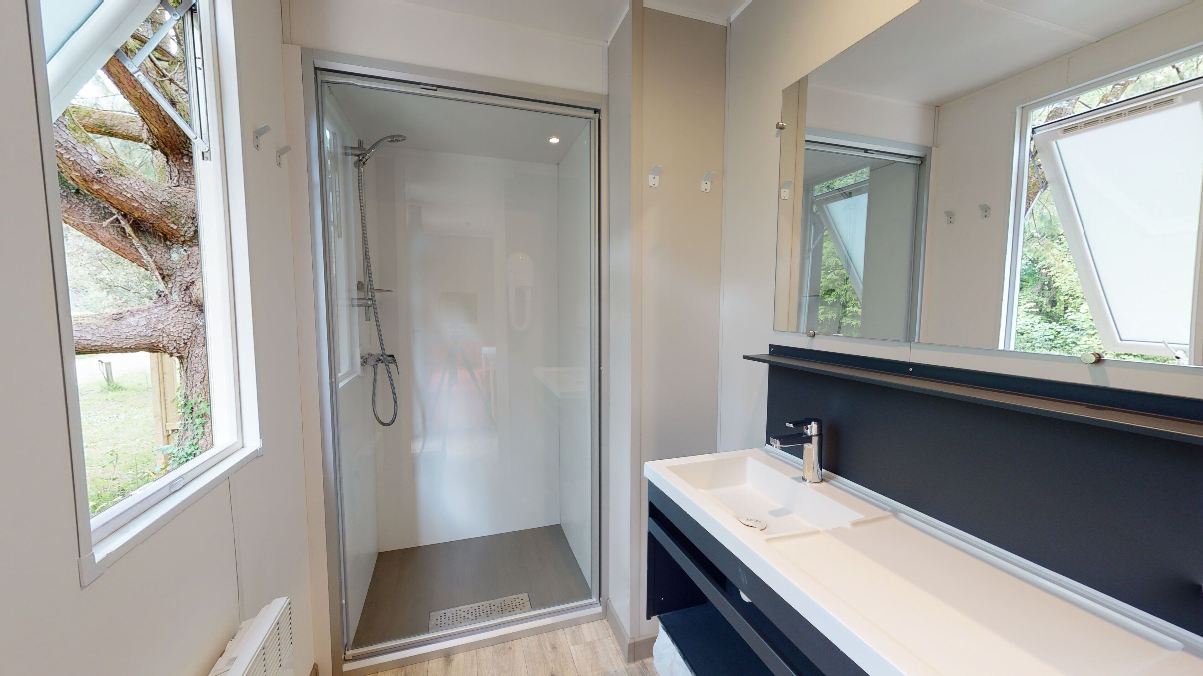 A modern bathroom with a glass shower enclosure, a white sink, and a large mirror.