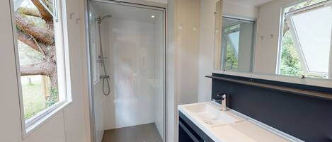 A modern bathroom with a glass shower enclosure, a white sink, and a large mirror.