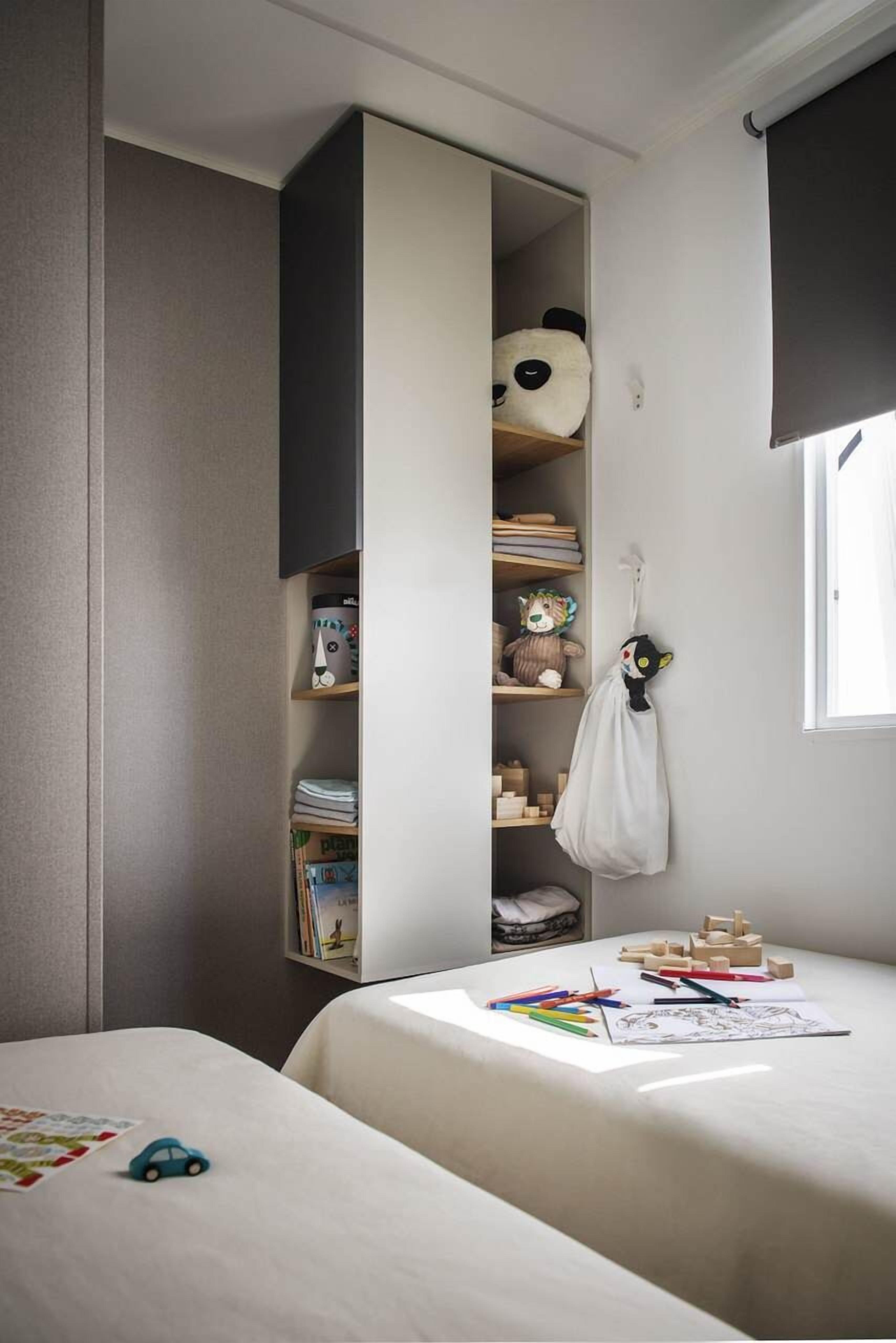A child's bedroom with a built-in bookshelf, a hanging toy, and a window.