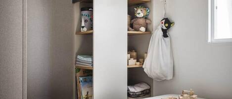A child's bedroom with a built-in bookshelf, a hanging toy, and a window.