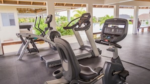 Une salle de sport équipée de vélos d’appartement, de tapis de course et d’un appareil d’aviron.