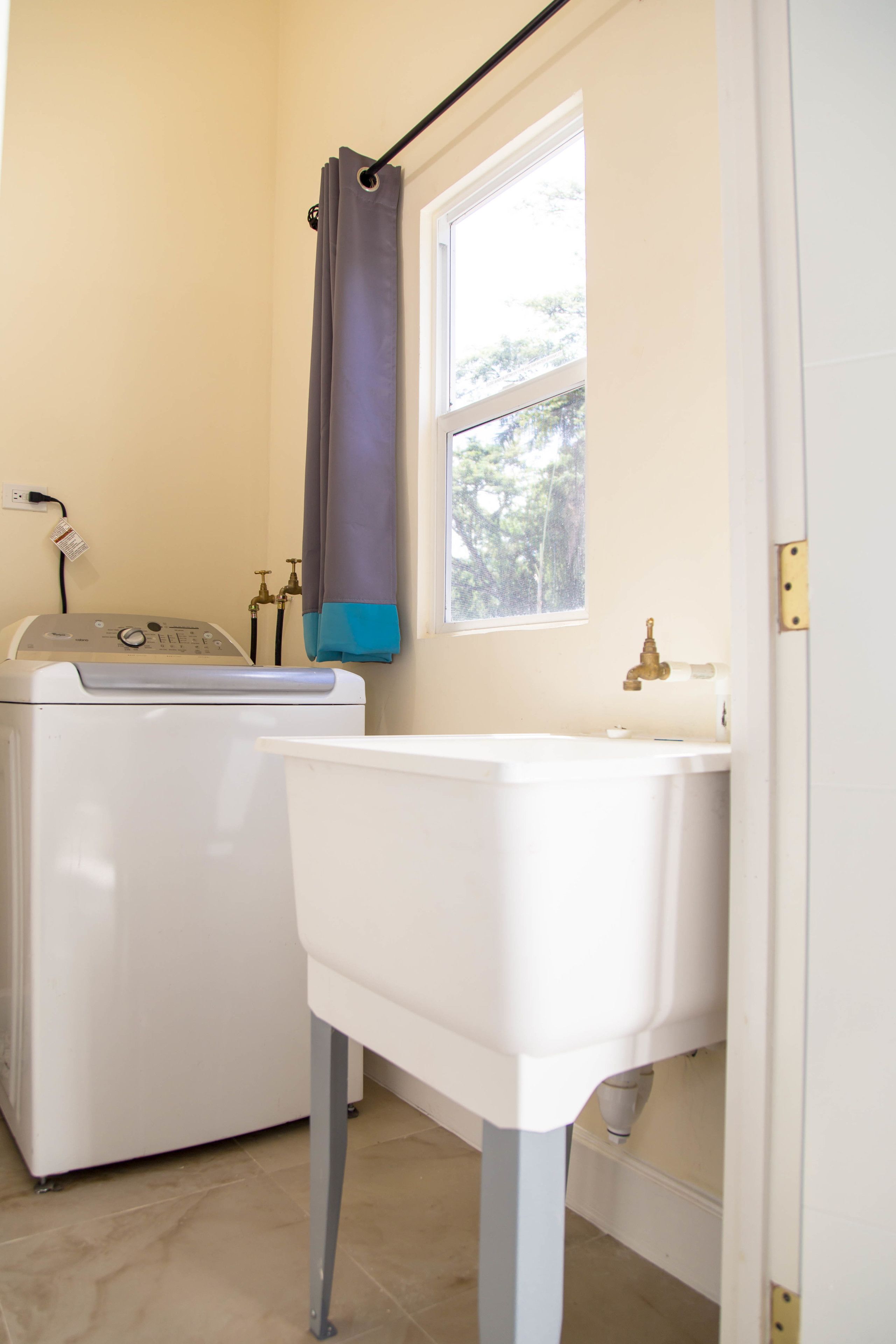 A laundry area with a washing machine, a sink, and a window.