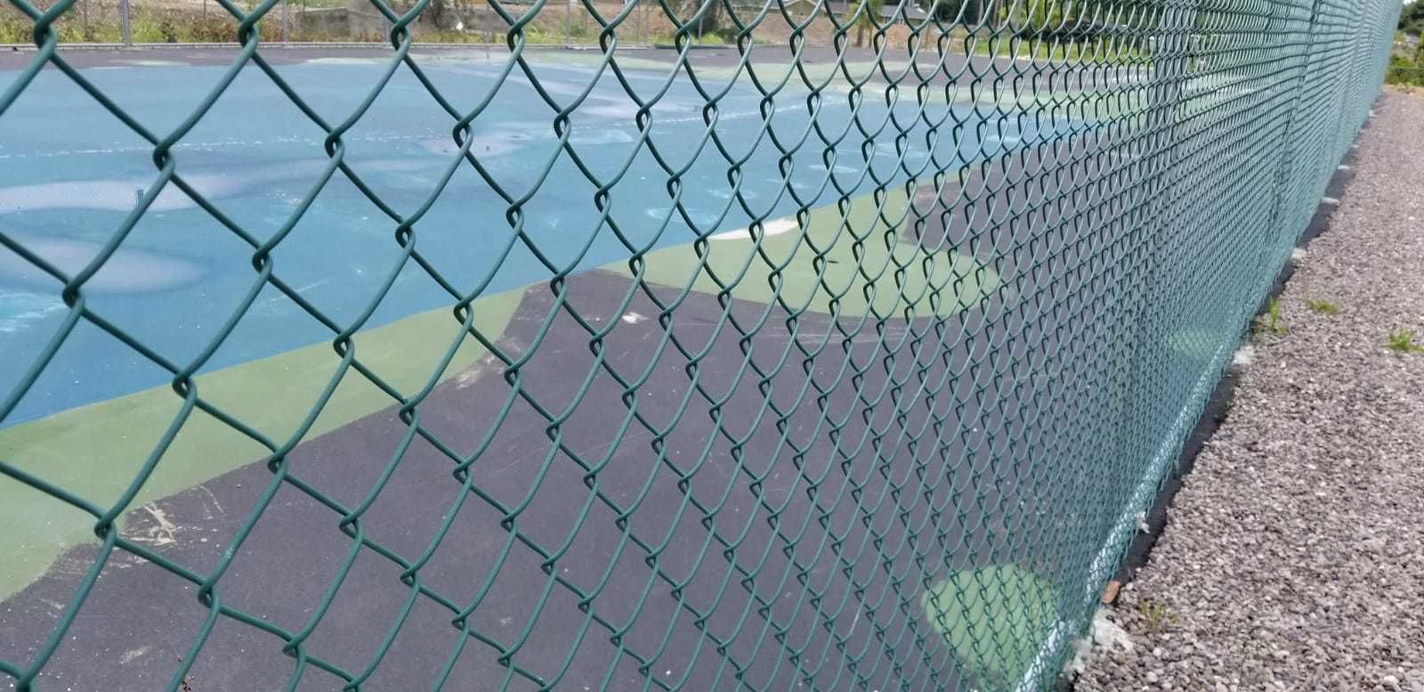 A chain-link fence surrounding a tennis court.