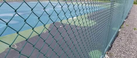 A chain-link fence surrounding a tennis court.
