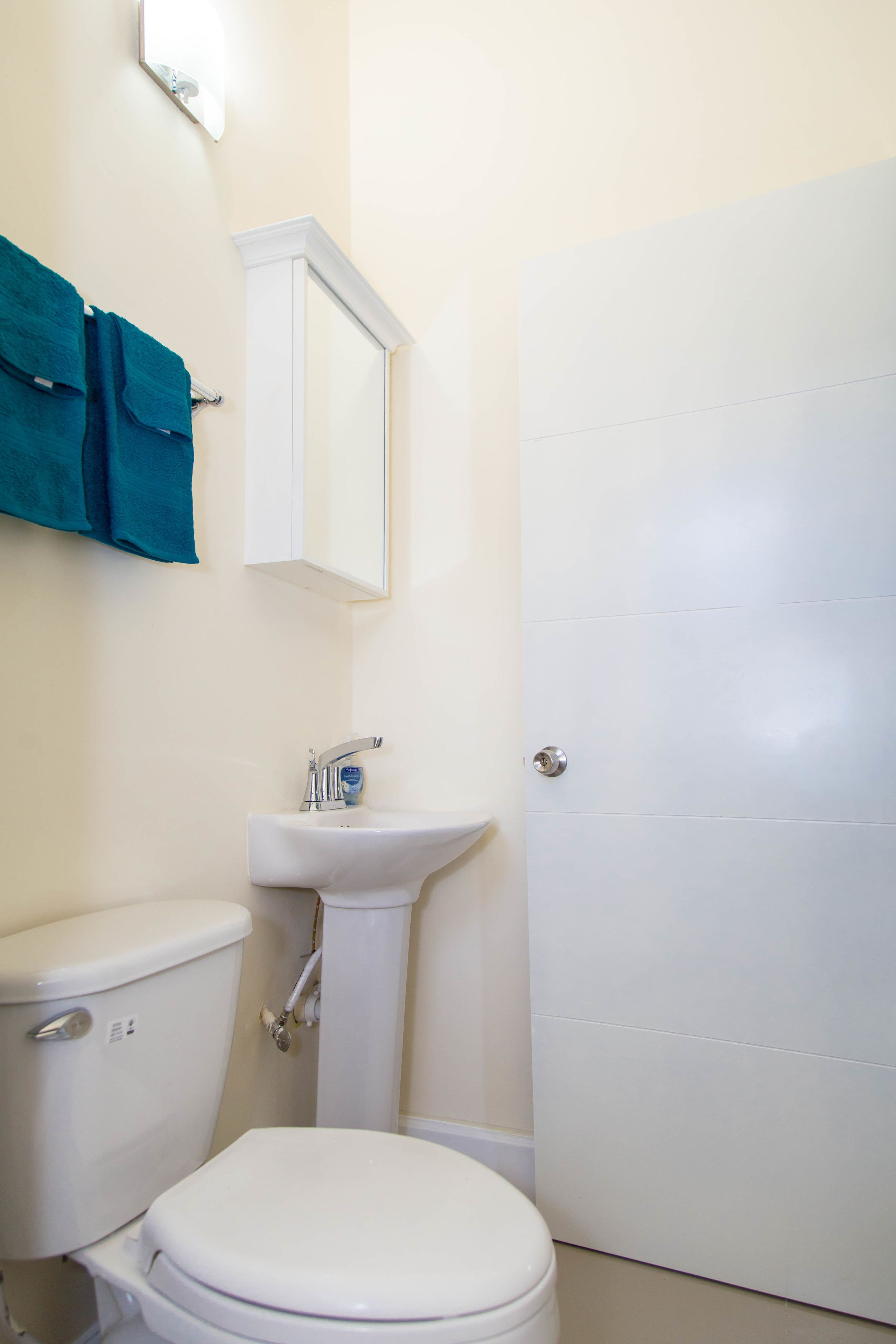A bathroom with a toilet, sink, and a door.