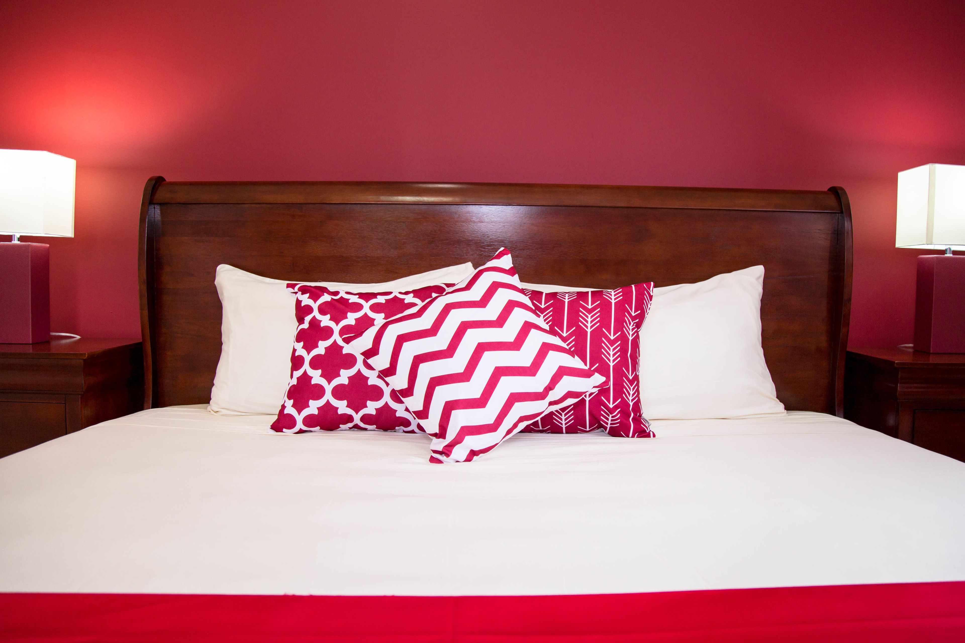 A neatly made bed with a wooden headboard, two bedside lamps, and patterned pillows.