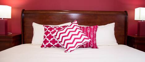 A neatly made bed with a wooden headboard, two bedside lamps, and patterned pillows.