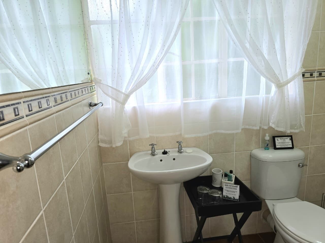A bathroom with a white sink, a toilet, and a small table with toiletries.