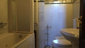Et badeværelse med badekar, toilet og håndvask.
