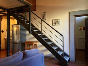 A staircase with metal railings leading to a second floor, a blue sofa, and a refrigerator in the foreground. - Ginori Double (Florence)