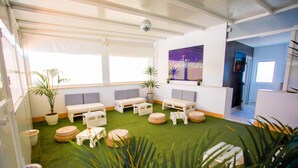 A room with a green artificial turf floor, white furniture, and potted plants.