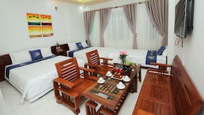 A hotel room with two beds, wooden furniture, a TV, and artwork on the wall. - An Binh Tai Hotel (Da Nang)