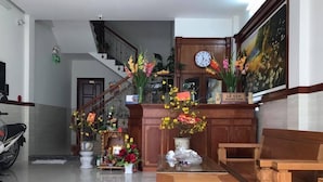 A reception area with a wooden reception desk, a clock, and a staircase leading upstairs. - An Binh Tai Hotel (Da Nang)