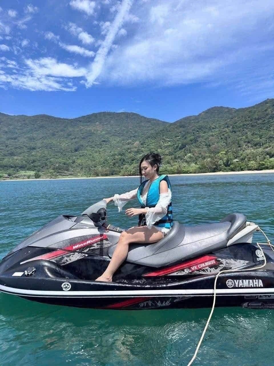 A person on a Yamaha jet ski in a body of water with a forested island in the background.