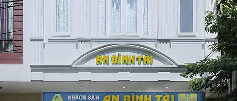 Fachada de hotel con un diseño arquitectónico clásico, que presenta una entrada destacada con un letrero que dice "KHÁCH SAN HOTEL AN BÌNH TÁI".