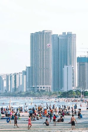 A beach with people and buildings in the background. - An Binh Tai Hotel (Da Nang)