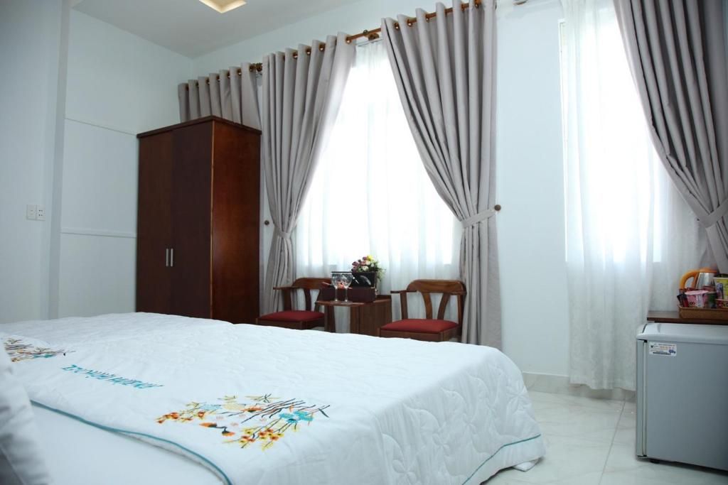 Habitación de hotel con cama, escritorio, silla, armario y un refrigerador pequeño.