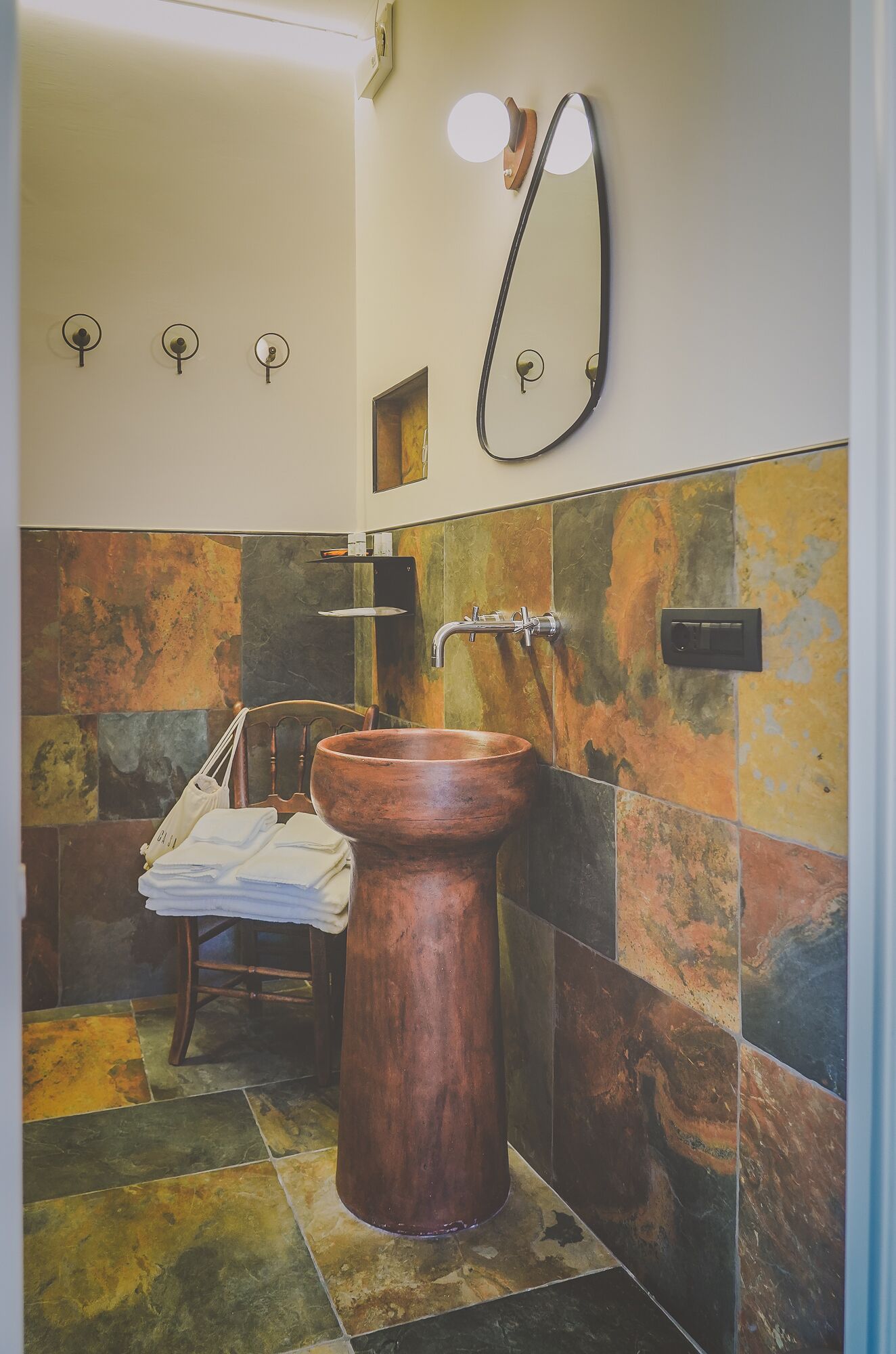 Un baño con un lavabo de madera, un perchero y un espejo.