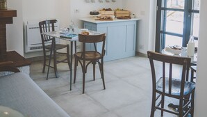 A modern kitchen with a dining area, featuring a central island, chairs, and a window with a view. - Casa Ziazì (Monopoli)