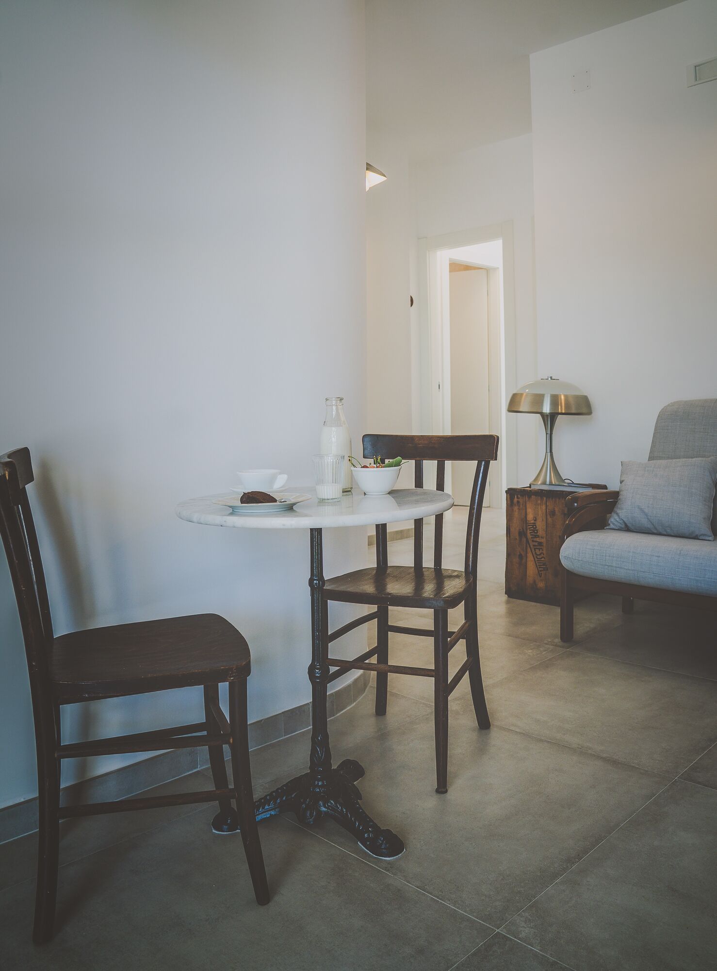 Un petit coin repas avec une table ronde, deux chaises, une lampe et un canapé.