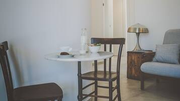 Un petit coin repas avec une table ronde, deux chaises, une lampe et un canapé.